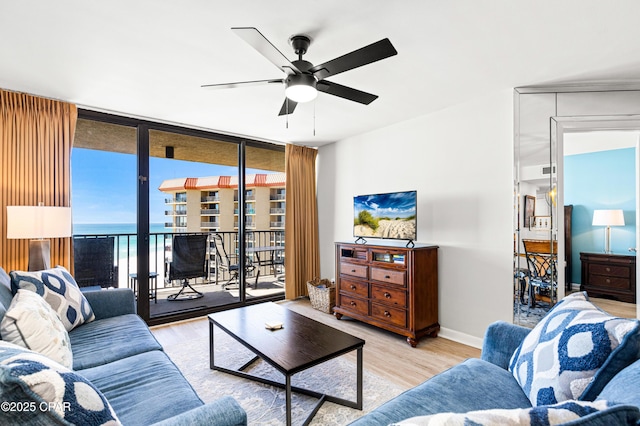 living room featuring baseboards, floor to ceiling windows, ceiling fan, and wood finished floors