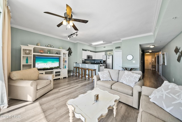 living room featuring ceiling fan, wood finished floors, baseboards, ornamental molding, and rail lighting