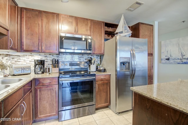 kitchen with light tile patterned floors, tasteful backsplash, visible vents, appliances with stainless steel finishes, and light stone counters