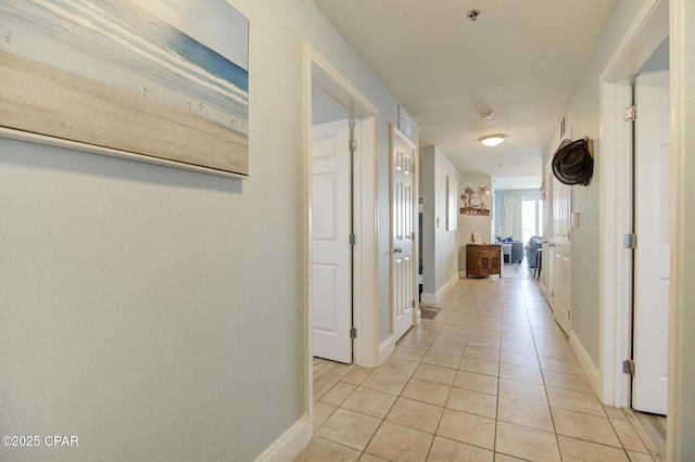 hall featuring baseboards and light tile patterned floors