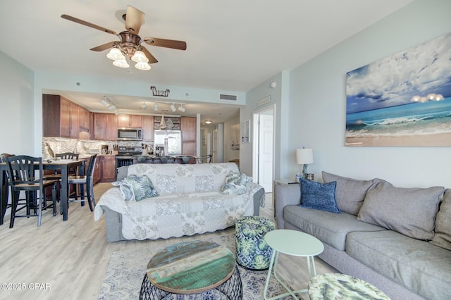 living area with ceiling fan, visible vents, and light wood-style floors