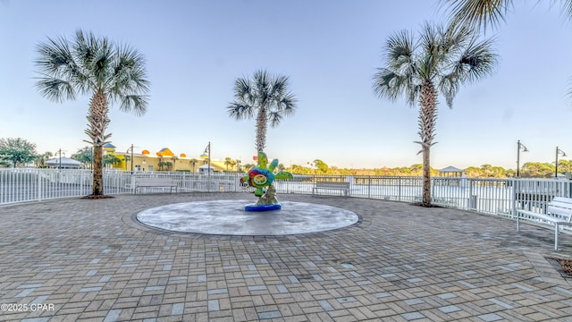 view of property's community with curved driveway, fence, and a patio