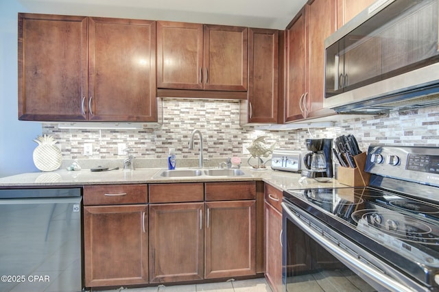 kitchen featuring appliances with stainless steel finishes, a sink, light stone countertops, and decorative backsplash