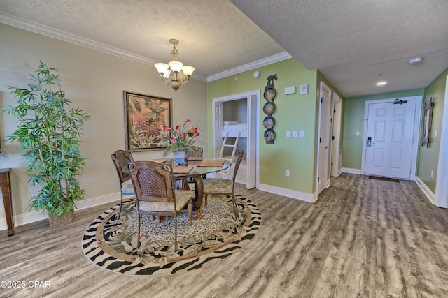 dining space with baseboards, a textured ceiling, an inviting chandelier, and wood finished floors