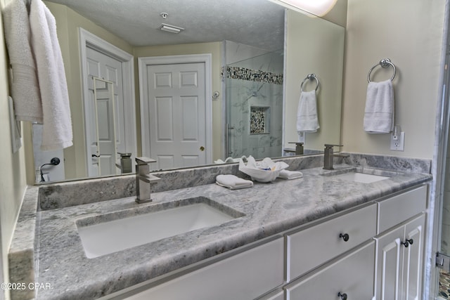 full bathroom with a stall shower, a sink, a textured ceiling, and double vanity