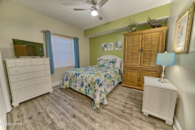 bedroom with baseboards, a textured ceiling, a ceiling fan, and light wood-style floors