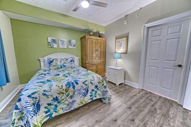 bedroom with a textured ceiling, ceiling fan, wood finished floors, and baseboards