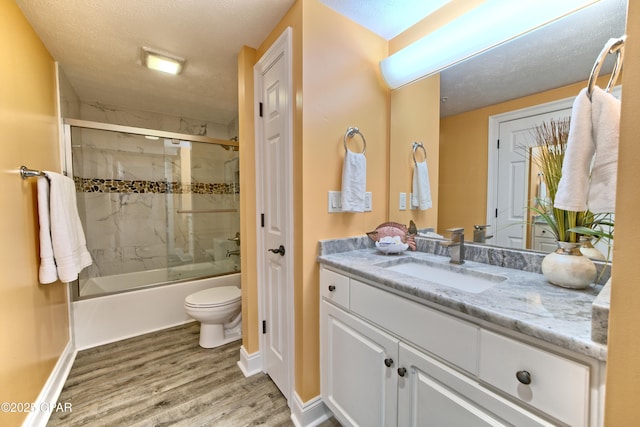 full bathroom with enclosed tub / shower combo, a textured ceiling, toilet, wood finished floors, and vanity