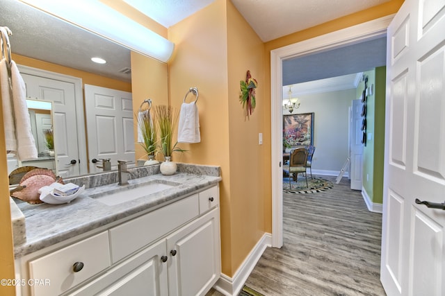 bathroom with an inviting chandelier, wood finished floors, vanity, and baseboards