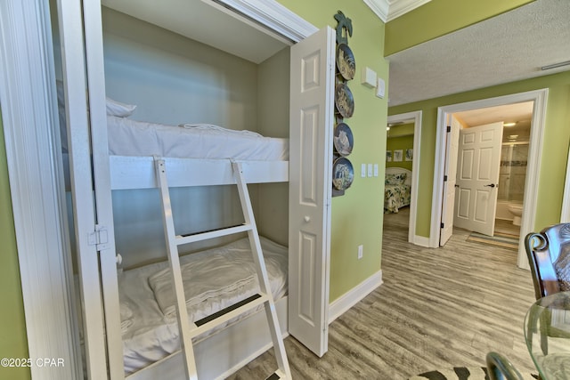 bedroom with visible vents, connected bathroom, baseboards, and wood finished floors