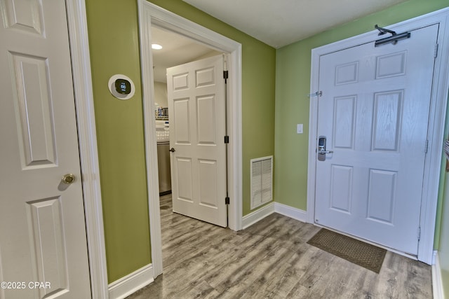 foyer with wood finished floors, visible vents, and baseboards