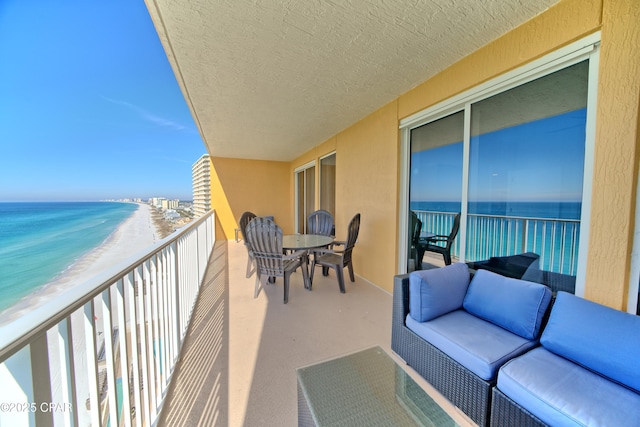 balcony featuring a water view, outdoor lounge area, and a beach view