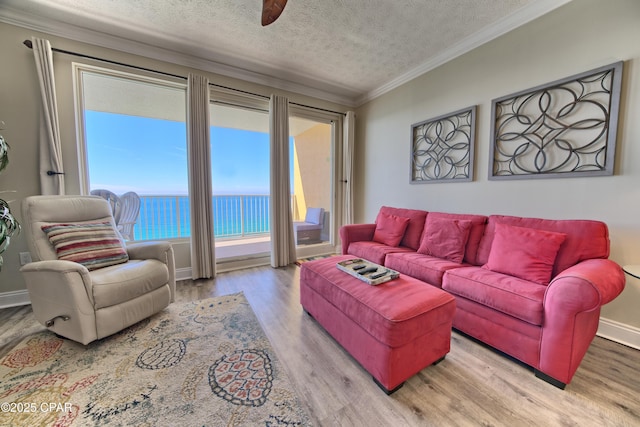 living room featuring crown molding, a water view, a textured ceiling, wood finished floors, and baseboards