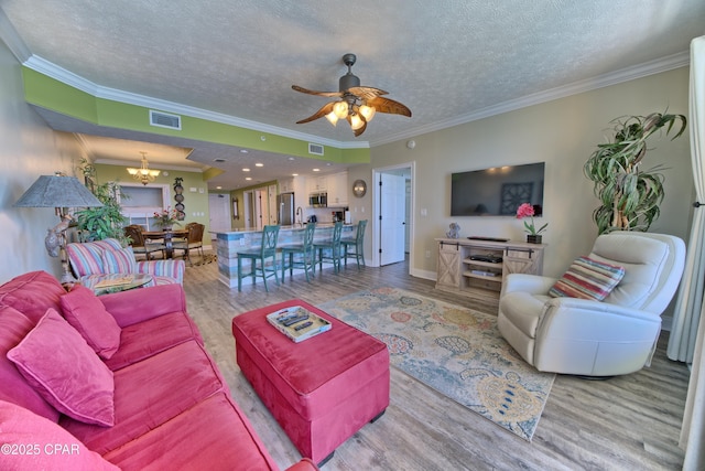 living room with a textured ceiling, visible vents, wood finished floors, and ceiling fan with notable chandelier