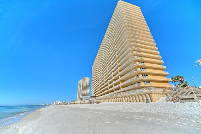 view of building exterior with a water view and a beach view