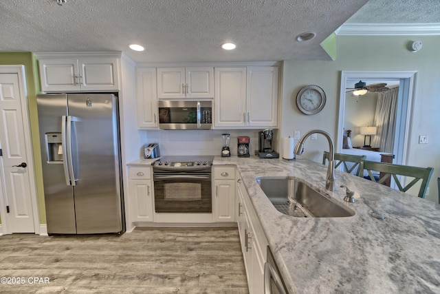 kitchen featuring light wood-type flooring, white cabinets, stainless steel appliances, and a sink