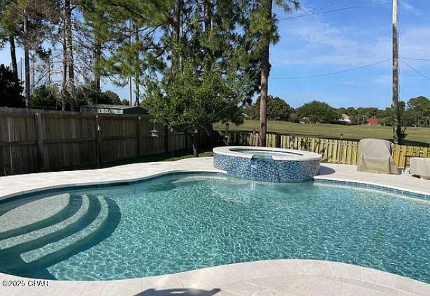 view of swimming pool featuring a pool with connected hot tub and a fenced backyard