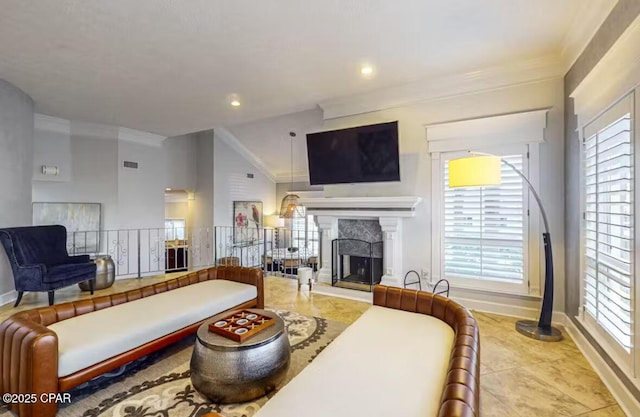 living room featuring a healthy amount of sunlight, a fireplace with raised hearth, and crown molding