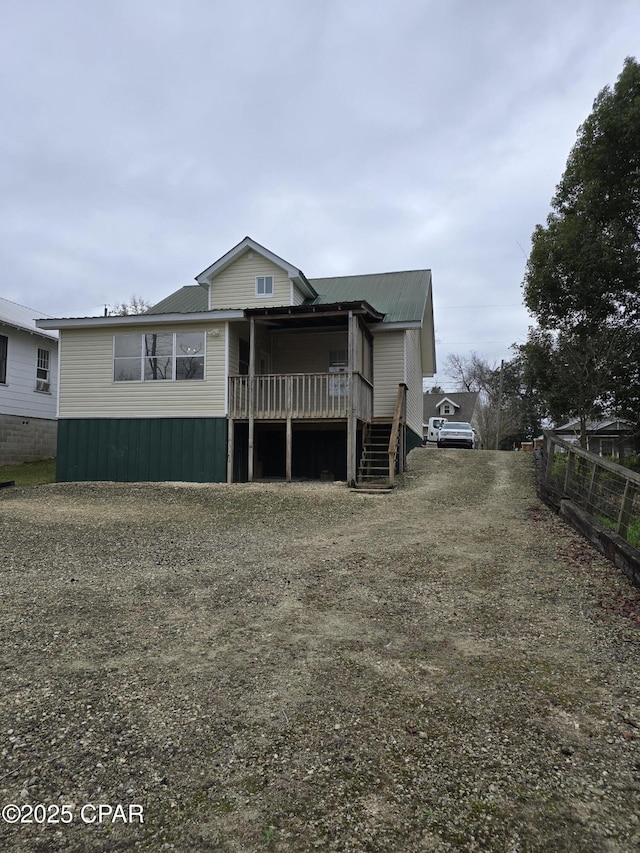 view of front facade featuring metal roof, stairway, a wooden deck, and fence