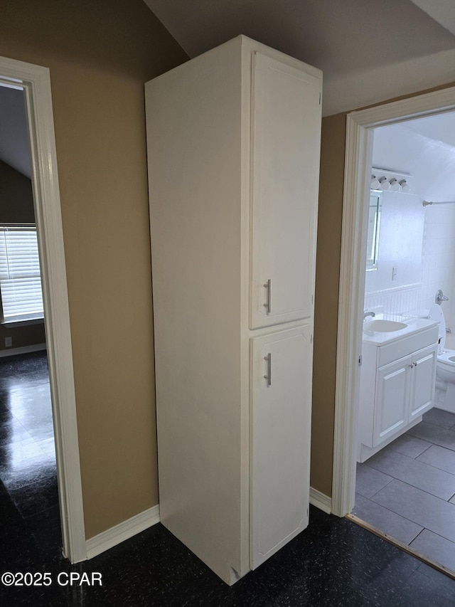 hallway featuring a sink and baseboards