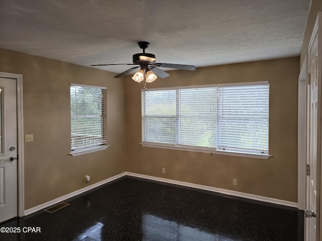 spare room featuring a ceiling fan, visible vents, a textured ceiling, and baseboards