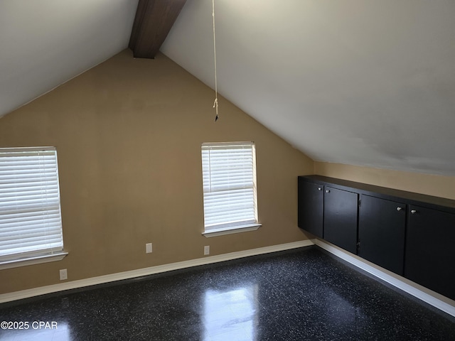 additional living space featuring vaulted ceiling with beams and baseboards