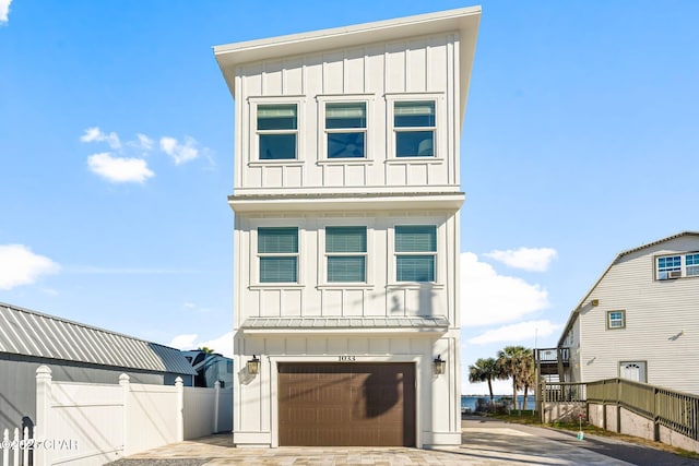 view of front of property featuring driveway, board and batten siding, an attached garage, and fence