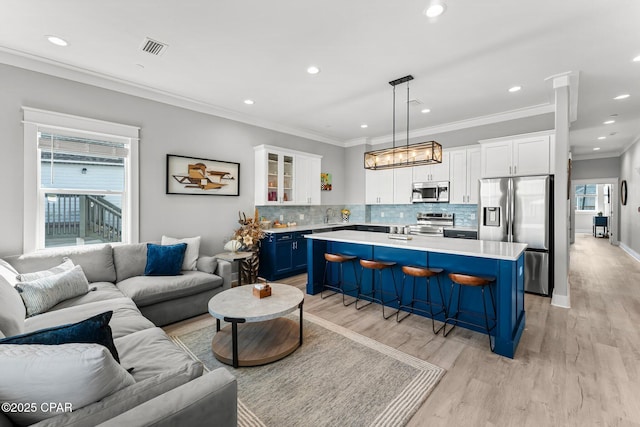 living area featuring light wood-type flooring, visible vents, recessed lighting, crown molding, and baseboards