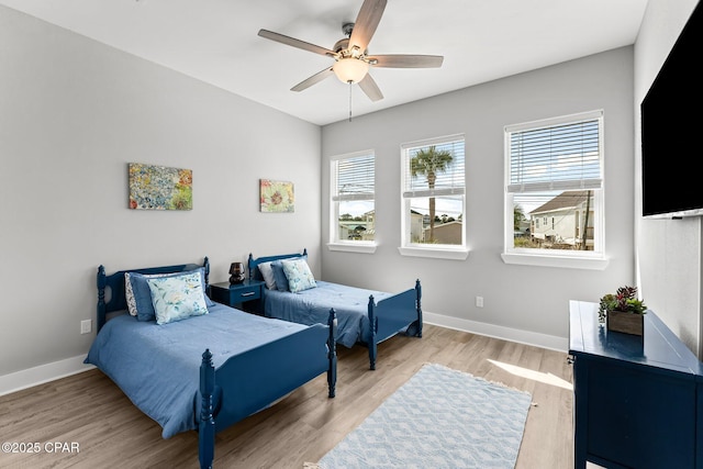 bedroom with multiple windows, baseboards, and wood finished floors