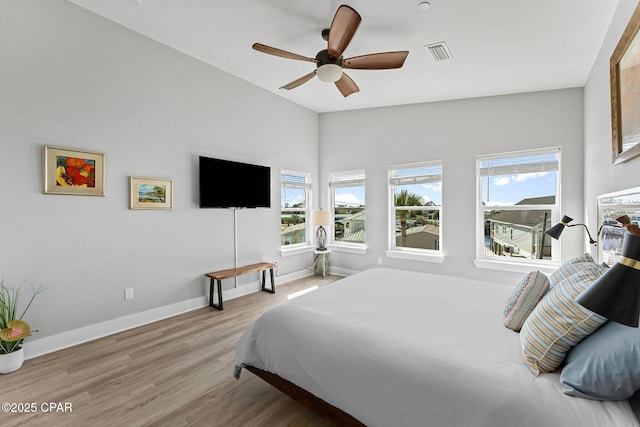 bedroom with wood finished floors, visible vents, baseboards, ceiling fan, and vaulted ceiling