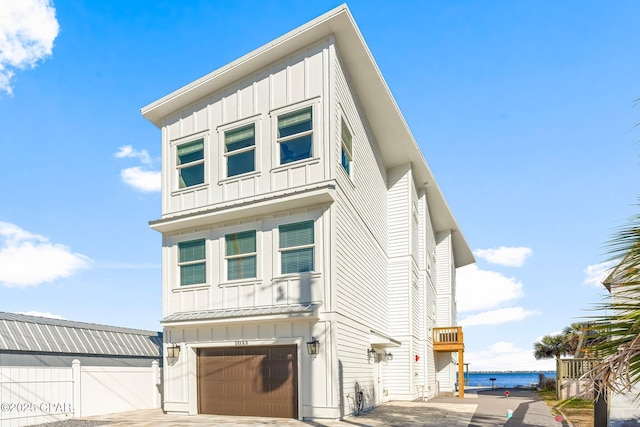 view of front of property with a garage, board and batten siding, concrete driveway, and fence