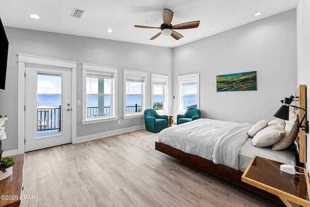 bedroom featuring access to exterior, visible vents, multiple windows, and wood finished floors