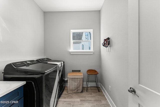 laundry area featuring washer and dryer, baseboards, and wood finish floors