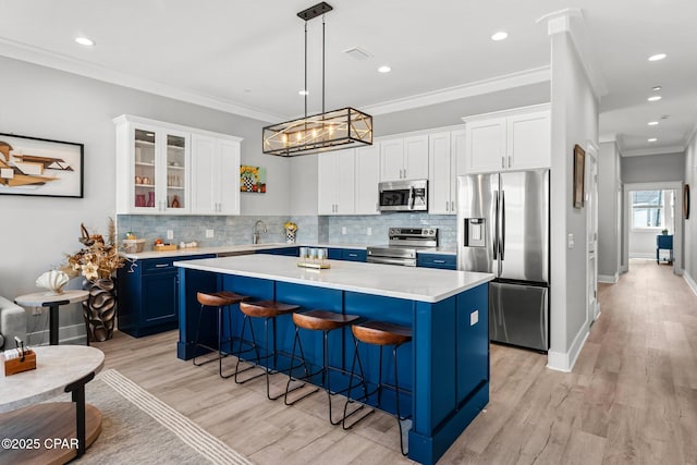 kitchen with blue cabinetry, stainless steel appliances, light wood-style floors, a kitchen breakfast bar, and a center island