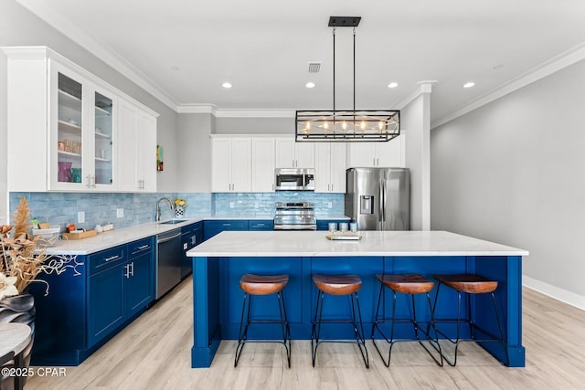 kitchen with visible vents, crown molding, appliances with stainless steel finishes, blue cabinets, and a sink