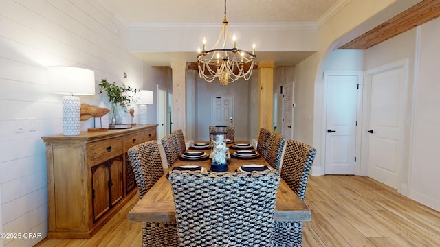 dining area featuring light wood-type flooring, ornamental molding, and a notable chandelier