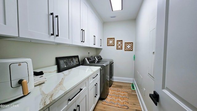 laundry room featuring light wood finished floors, cabinet space, visible vents, washing machine and dryer, and baseboards