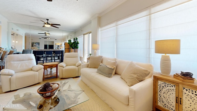 living area with crown molding, ceiling fan, a textured ceiling, and wood finished floors