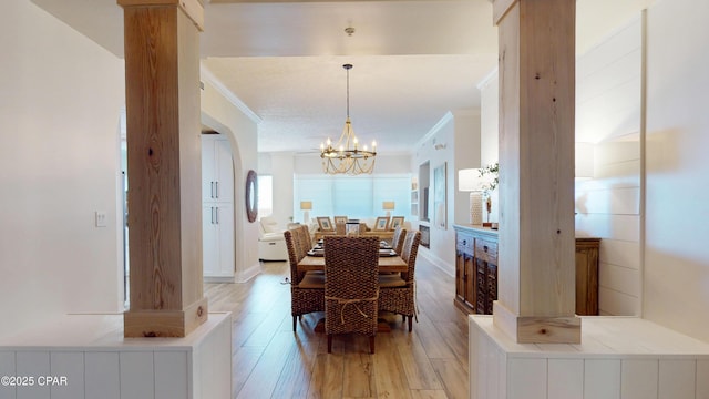 dining space with a chandelier, crown molding, light wood-style flooring, and baseboards