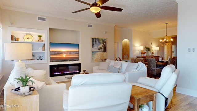 living area featuring light wood-type flooring, visible vents, a textured ceiling, and ornamental molding