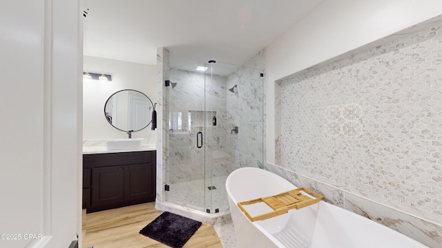 full bath with a freestanding tub, a marble finish shower, wood finished floors, and vanity