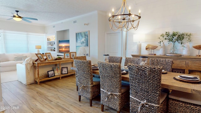 dining space featuring built in shelves, visible vents, light wood-style floors, ornamental molding, and a textured ceiling