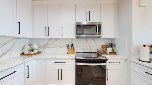 kitchen featuring tasteful backsplash, stainless steel microwave, light stone countertops, white cabinetry, and range with electric stovetop