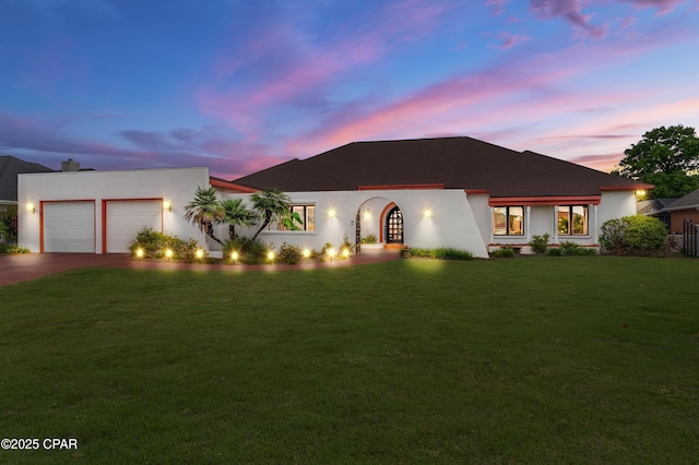 view of front of home with driveway, a garage, a front lawn, and stucco siding