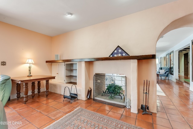 living area featuring arched walkways, a fireplace, and light tile patterned flooring