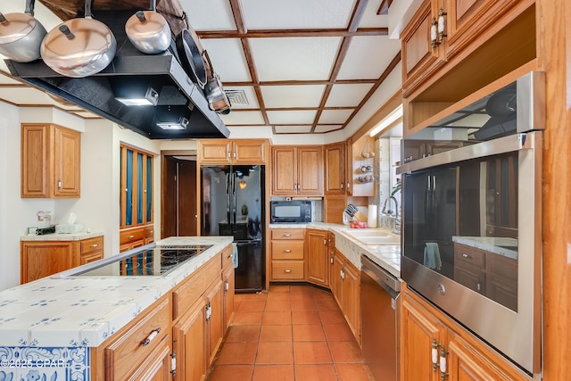 kitchen featuring light tile patterned floors, a kitchen island, a sink, visible vents, and black appliances