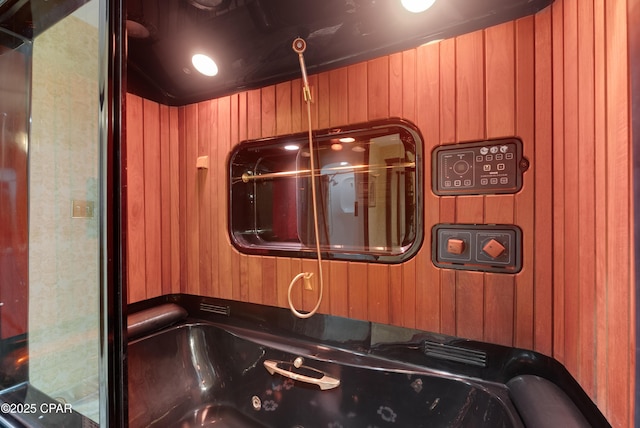 interior space with a tub with jets and wood walls