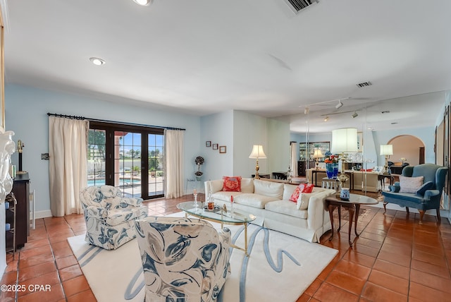 living area featuring arched walkways, french doors, visible vents, and tile patterned floors