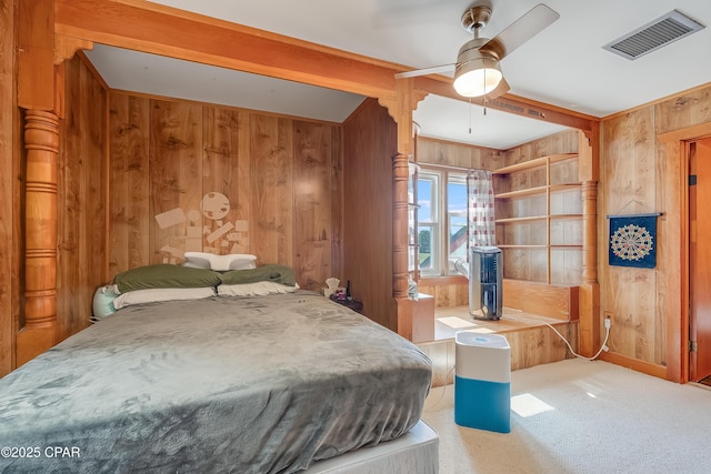 bedroom with carpet floors, wooden walls, visible vents, and beam ceiling