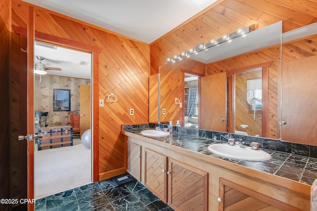 full bath featuring toilet, wood walls, double vanity, and a sink